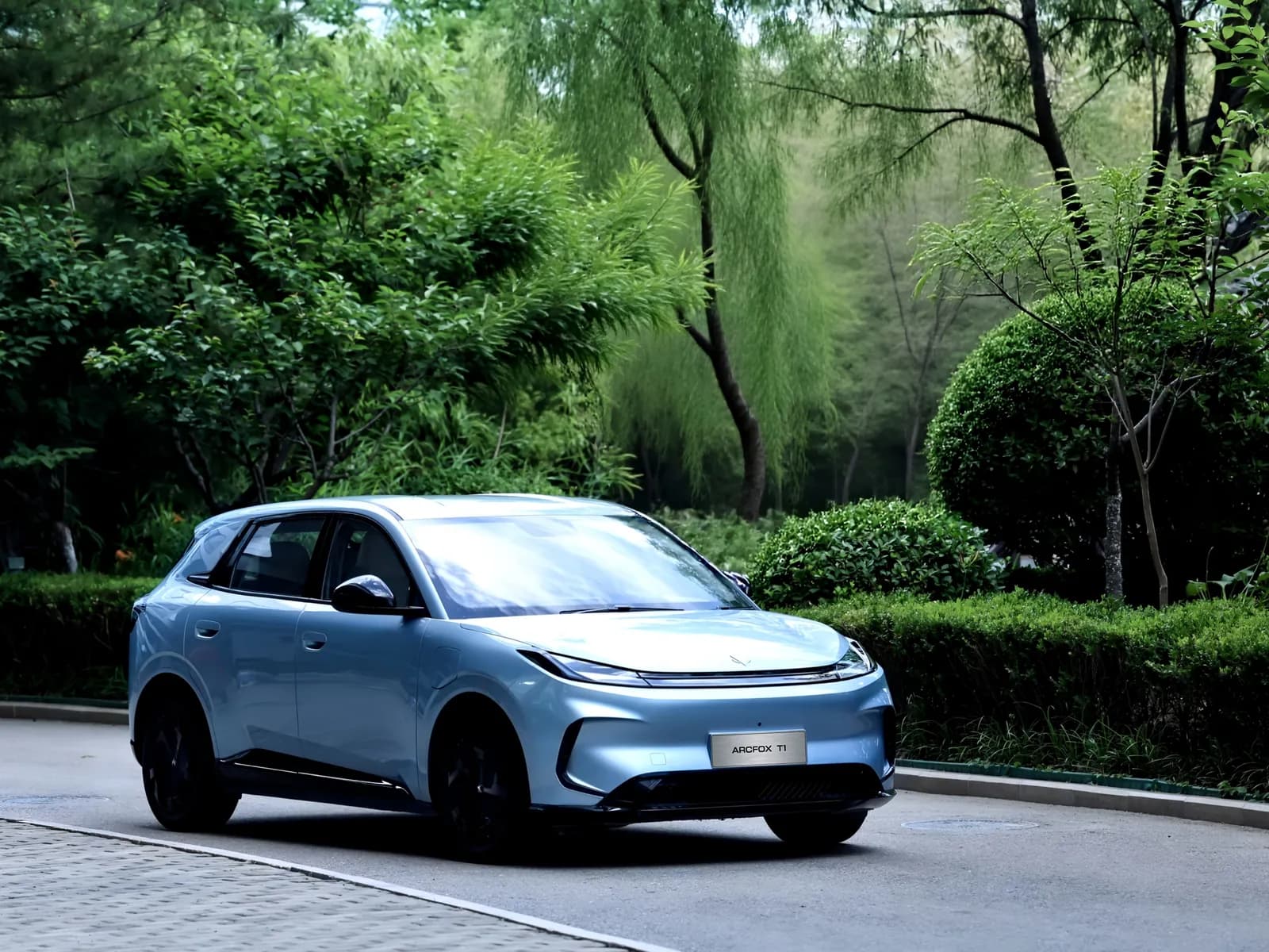 Silver ARCFOX T1 on a tree-lined garden road